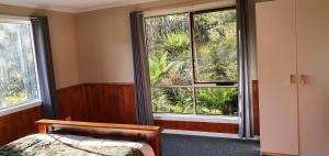 a bedroom with a bed and two large windows at Cradle Alpine Retreat in Moina