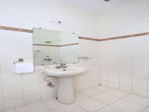 Baño blanco con lavabo y espejo en Hotel Paradise Chandigarh, en Chandīgarh