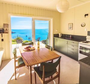 a kitchen and dining room with a table and a view of the ocean at Incredible Bay Views - Kaiteriteri Bach in Kaiteriteri