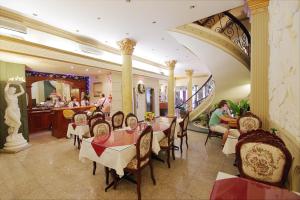 a restaurant with tables and chairs and a woman sitting at it at The Spring Hotel in Ho Chi Minh City