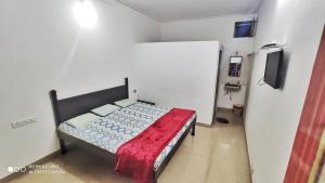 um pequeno quarto com uma cama e uma televisão em Chandraprabha Nyahari Niwas em Malvan