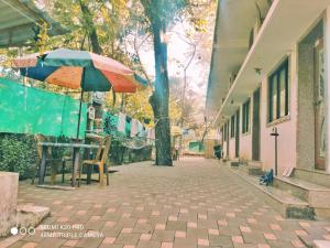 uma mesa e cadeiras com um guarda-sol numa rua em Chandraprabha Nyahari Niwas em Malvan