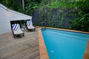 a swimming pool on a wooden deck with two chairs at Port Douglas Cottage & Lodge in Port Douglas