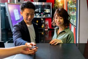 a man and woman sitting at a table looking at a cell phone at Hotel Benkyo Beya Amagasaki in Amagasaki