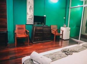 a bedroom with green walls and a bed and chairs at Thaweesuk Heritage Homestay in Phangnga