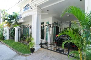 a white house with a black gate with plants at Ge JacMart Homestay Makassar in Makassar