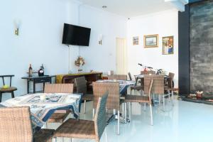 a dining room with tables and chairs and a tv at Ge JacMart Homestay Makassar in Makassar