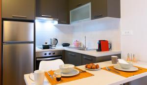 a kitchen with a table and a stainless steel refrigerator at Elounda Colour Apartments in Elounda