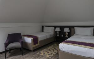 a small room with two beds and a chair at Hotel Alibi Sabac in Šabac