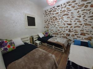 una camera da letto con due letti e un muro di pietra di maison la branche d oiseaux a Douar Annbirat
