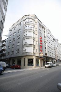 duży budynek przy ulicy miejskiej z zaparkowanymi samochodami w obiekcie Hotel HHB Pontevedra Confort w mieście Pontevedra