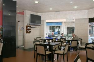 ポンテベドラにあるHotel HHB Pontevedra Confortのテーブルと椅子、薄型テレビ付きのレストランを提供しています。