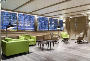 una sala de espera con sillas verdes, mesas y ventanas en Hotel Panorama, en Andorra la Vella