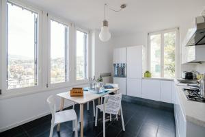una cucina con armadi bianchi, tavolo e sedie di Modern Luxury Attic - byMyHomeInComo a Como