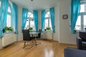 ein Esszimmer mit blauen Vorhängen sowie einem Tisch und Stühlen in der Unterkunft Haus Metropol 2-Raum-Apartment - Nr. 10 in Binz