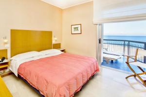 a bedroom with a bed and a balcony with the ocean at Hotel Tirreno in Spotorno