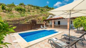einen Pool mit Sonnenschirm und Stühlen und ein Haus in der Unterkunft Villa Belen Torrox by Ruralidays in Torrox