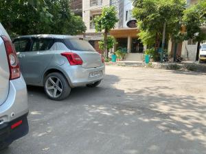 een zilveren auto geparkeerd aan de kant van een straat bij Hotel Amritsar International in Amritsar