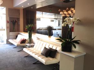 a living room with two white couches and flowers at Hôtel Ligure in Cannes