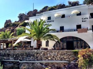a hotel with a palm tree in front of it at Hotel Porto Loutro on the Hill in Loutro