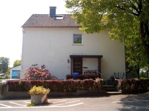 a white house with a door and some flowers at Ferienwohnung Bergisch Land in Wermelskirchen
