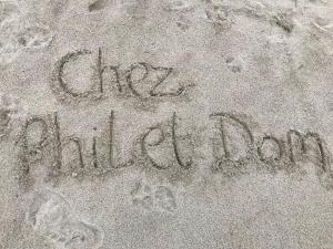 a sign written in the sand on a beach at Chez Phil et Dom in Biarritz