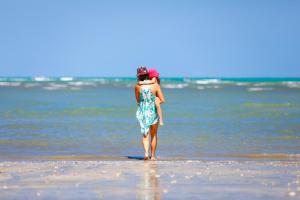 a woman in a dress standing on the beach at Sollaris Ecopousada in Japaratinga