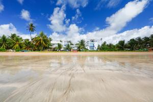 a beach with palm trees and a building in the background at Sollaris Ecopousada in Japaratinga