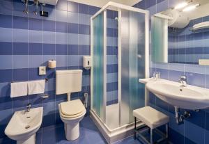 bagno piastrellato blu con servizi igienici e lavandino di Hotel Fonzari a Grado