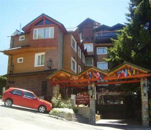 a red car parked in front of a large building at Ruca Cheli Village Ski Hotel in San Carlos de Bariloche