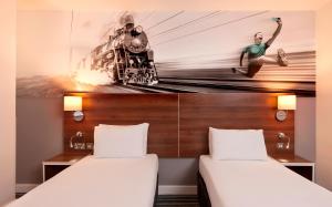 two beds in a room with a mural of a train at Heeton Concept Hotel - City Centre Liverpool in Liverpool