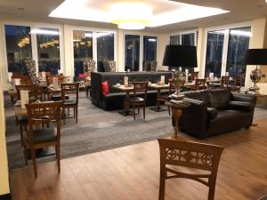 un restaurante con sofás, mesas, sillas y ventanas en Eden-Hotel, en Gotinga