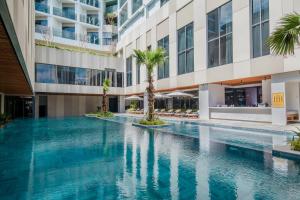 a swimming pool in the middle of a building with palm trees at Fleur de Lys Hotel Quy Nhon in Quy Nhon