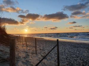 um pôr-do-sol numa praia com o oceano em Hotel Continental em Krynica Morska