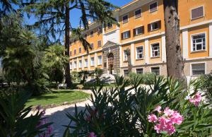 budynek z palmami i kwiatami w parku w obiekcie LH Hotel Excel Roma Montemario w Rzymie