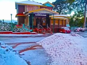 a snow covered building with a car parked in front at Aaroham Resort by Aamod at Dharamshala ! Luxury Boutique Resort in Dharamshala