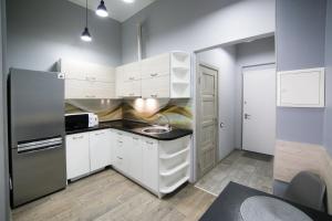 a kitchen with white cabinets and a stainless steel refrigerator at Lviv4U in Lviv
