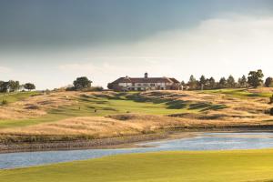 a house on top of a hill next to a river at The Oxfordshire Golf & Spa Hotel in Thame
