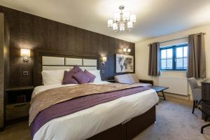 a bedroom with a large bed with purple pillows at The White Swan in Scotter