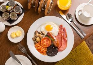 a plate of breakfast food with eggs beans and bacon at The Oxfordshire Golf & Spa Hotel in Thame