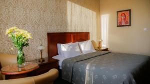 a bedroom with a bed and a table with a vase of flowers at Hotel Bankya Palace in Bankya