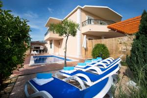 een rij blauwe en witte ligstoelen naast een zwembad bij Apartment Sasso in Split