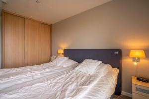 ein Schlafzimmer mit einem großen weißen Bett mit zwei Lampen in der Unterkunft Appartementencomplex Juliana 116 in De Koog