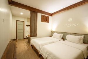 two beds in a room with a sign on the wall at Sang Poy Cottage in Ban Kung Mai Sak