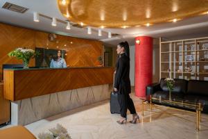 a woman standing at a bar in a lobby at Hotel Brascos in Rethymno Town