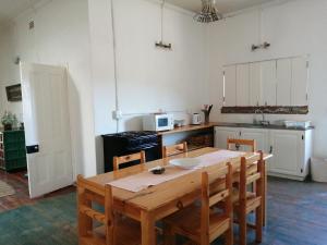 a kitchen with a wooden table and chairs and a kitchen with white cabinets at Aandster in Nieu-Bethesda