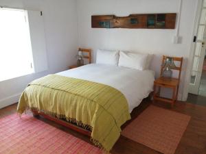 a bedroom with a bed with a yellow blanket on it at Aandster in Nieu-Bethesda