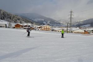 zwei Menschen fahren auf einer schneebedeckten Piste Ski in der Unterkunft Hotel Starjet in Flachau