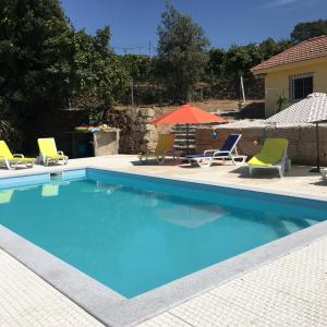 una piscina con 2 sillas de césped y una sombrilla en Casa Da Calçada, en Castelo de Paiva