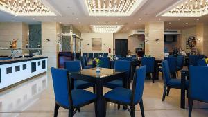 a restaurant with blue chairs and a table in a room at The Proud Hotel Al Khobar in Al Khobar